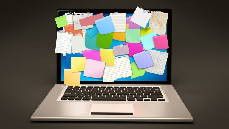 Meja kerja remote dengan laptop dan catatan rencana